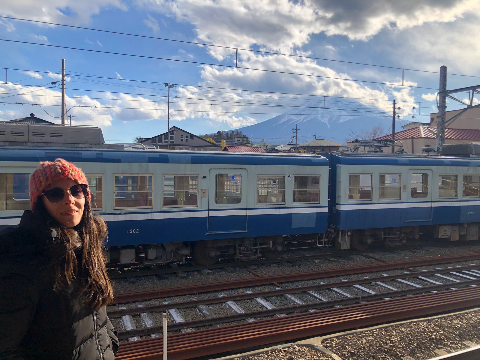 Mujer en estación de tren. Vagones de tren y Monte Fuji detrás. Invierno en Japón